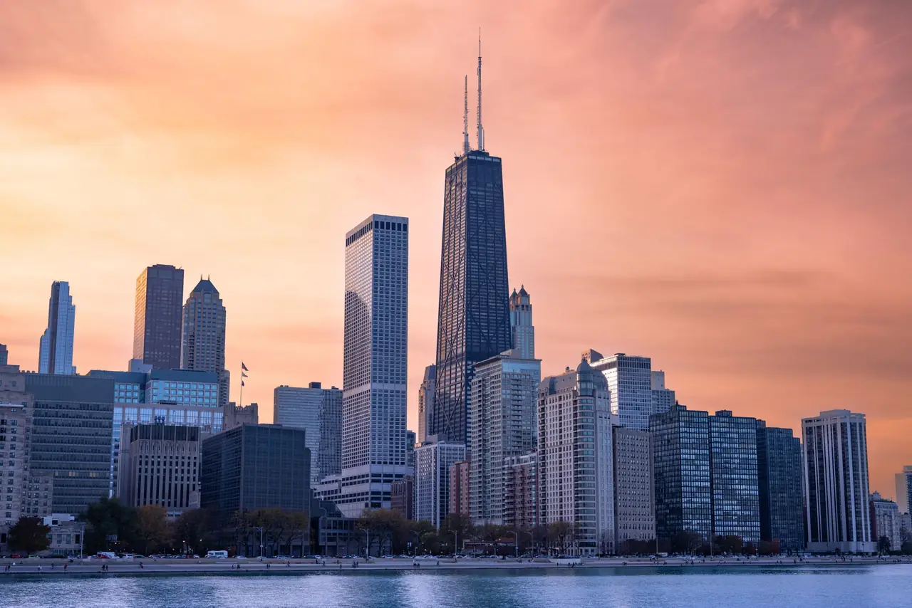 Chicago's skyline at sunset across the lakefront, led by the twin-antenna John Hancock Center